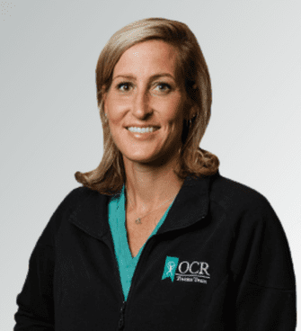 Amber Vance woman smiling, wearing a black jacket and a medical scrubs
