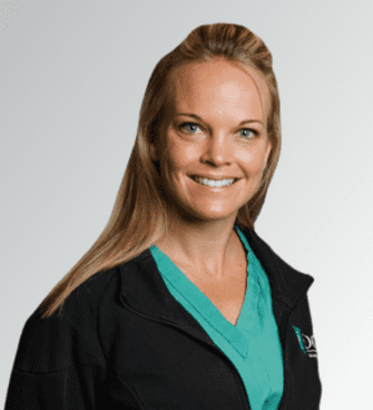 Brandy Fall A smiling woman with long blonde hair, identified as Brandy Fall, is wearing a green scrub top under a black jacket. She has blue eyes and stands against a simple white background.