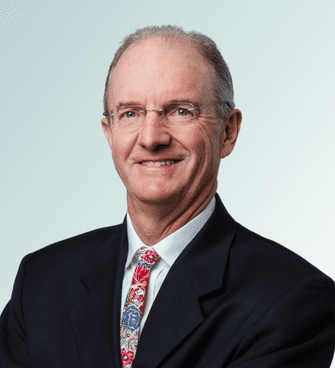 FitzGibbons Robert FitzGibbons, MD, a middle-aged man with short gray hair and glasses, is wearing a dark suit, white shirt, and colorful paisley tie. He is smiling and posing with his arms crossed against a light gradient background.