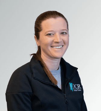 12 woman smiling, wearing a black jacket and a medical scrubs