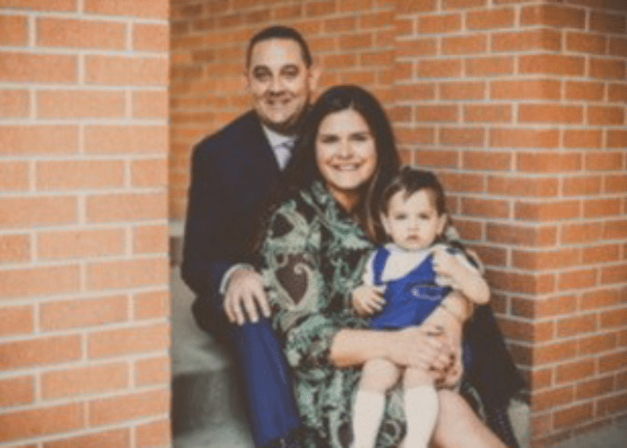 Chaus 1 a family of three posing in front of a brick wall