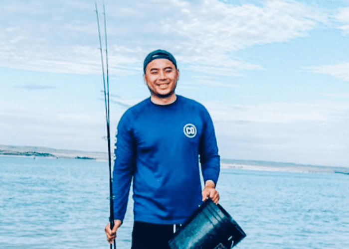 Le 1 A man holding a fishing pole and bucket in a blue shirt