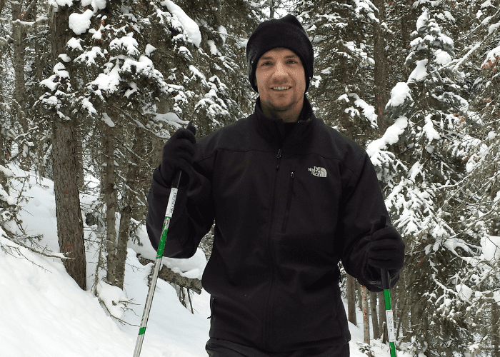ebel 3 a man standing in a black snow suit in the woods