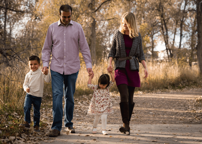 shah 2 A man and woman with two children walking down a path in fall