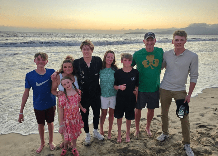 a family of 7 standing on a beach in front of the ocean at sunset a family of 7 standing on a beach in front of the ocean at sunset