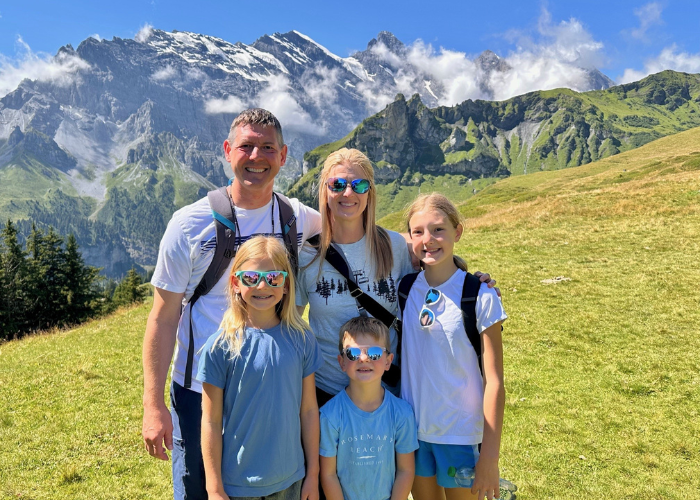 HArtman 5 A family of 5 with back packs on standing in front of a mountain on a hike