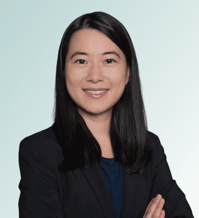 Tammy Ng Dr. Tammy Ng, MD, with straight black hair, wearing a dark blazer and navy top, smiles confidently with arms crossed against a light blue gradient background.