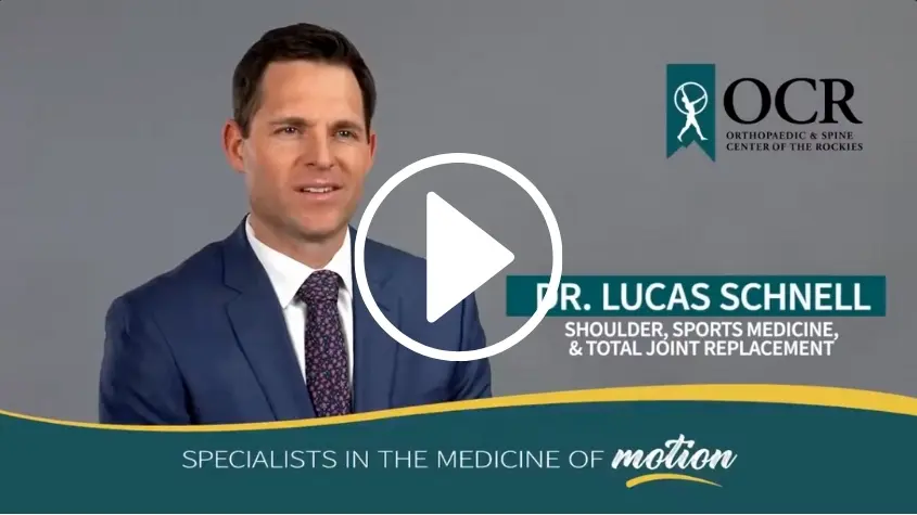 video dr schnell A doctor in a suit speaks in front of a gray background with the OCR logo. Text reads: "Dr. Lucas Schnell, Shoulder, Sports Medicine, & Total Joint Replacement. Specialists in the Medicine of Motion.