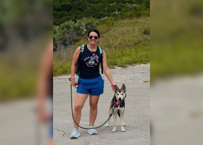 Dr. Machado standing in front of a hill with her dog
