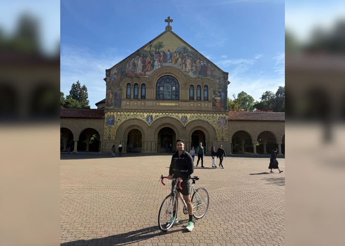 Dr. Robert Matar sitting on a bike in front of a beautiful building