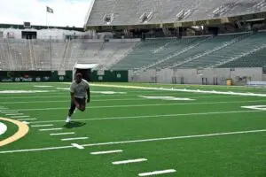 Mukendi Wa-Kalonji sprints across the turf of a large, empty Rams Football stadium.