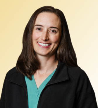 Amy Lagreca Amy LaGreca, PA-C, with long brown hair, wearing a black jacket over green medical scrubs, smiles at the camera in front of a light yellow gradient background.